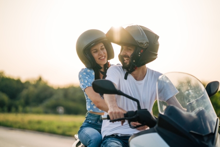 Happy young couple riding on a motorcycle on the road