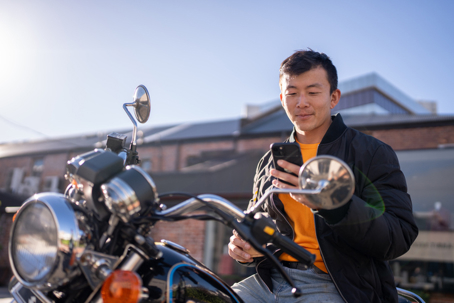 Man Sitting on Motorcycle Using Smartphone stock photo