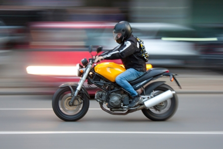 One man riding a motorbike on city street in motion