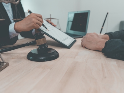 A notary or notary works with contract documents and knocks with a gavel in a legal courtroom. A lawyer advises clients during legal discussions. stock photo