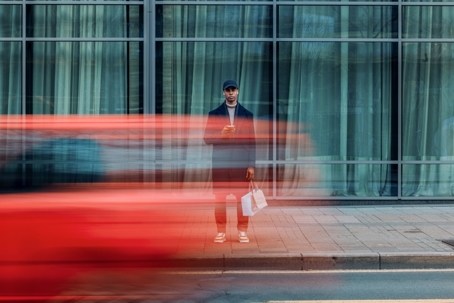 Urban Scene of Man in Motion With a Passing Red Vehicle stock photo