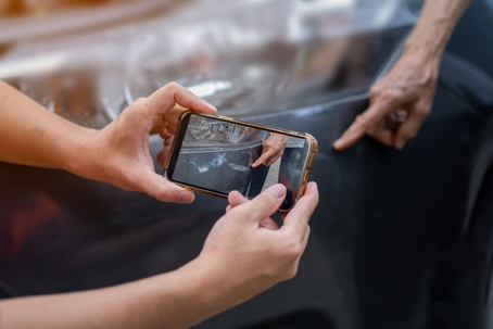 Insurance man inspecting a broken car after an accident as evidence for making an insurance claim stock photo