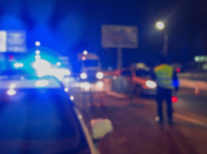 Unrecognizable blurry police car lights and police force officer on night road background, crime scene, night patrolling the city