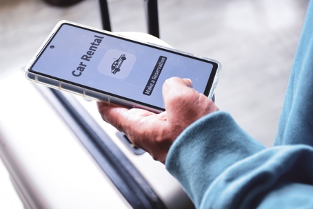 Close up of a person using his phone for car rental upon arrival