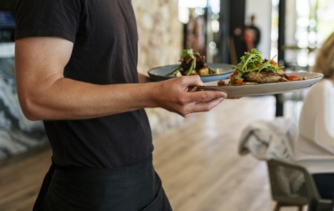 Waiter serving dish to guests at a restaurant stock photo