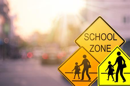 School zone warning sign on blur traffic road with colorful bokeh light abstract background. Copy space of transportation and travel concept. Vintage tone color style. stock photo