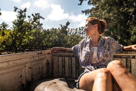 Young woman looking at view on pick-up truck on agricultural field stock photo