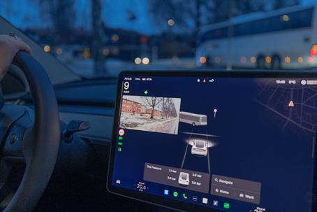 Female driver in Tesla Model Y electric car using autopilot with side camera view on winter street.