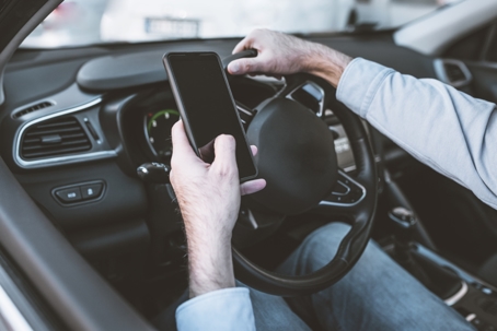 Dangerous driving while writing SMS text message. Man with mobile phone in hand and young woman in a car speedy driving on highway. stock photo