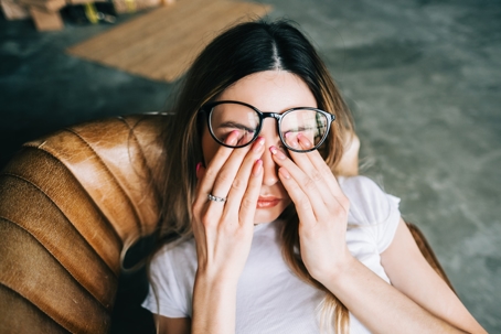 Young woman rubs her eyes after using glasses. Eye pain or fatigue concept. stock photo