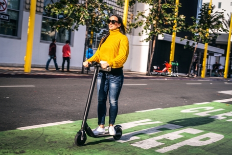 A woman driving an electric scooter on a scooter & bike lane in the city downtown stock photo