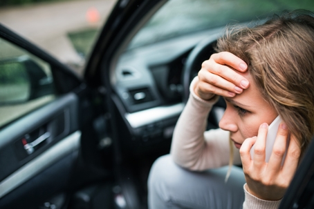 Young woman in the damaged car after a car accident, making a phone call. stock photo