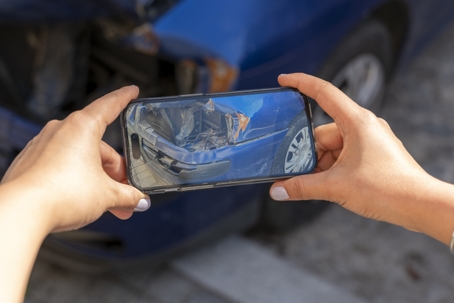 Man agent takes pictures of damage to car after accident by smartphone stock photo